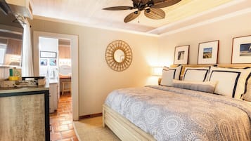 Un dormitorio con cama, ventilador de techo, espejo en la pared y cuadros enmarcados.