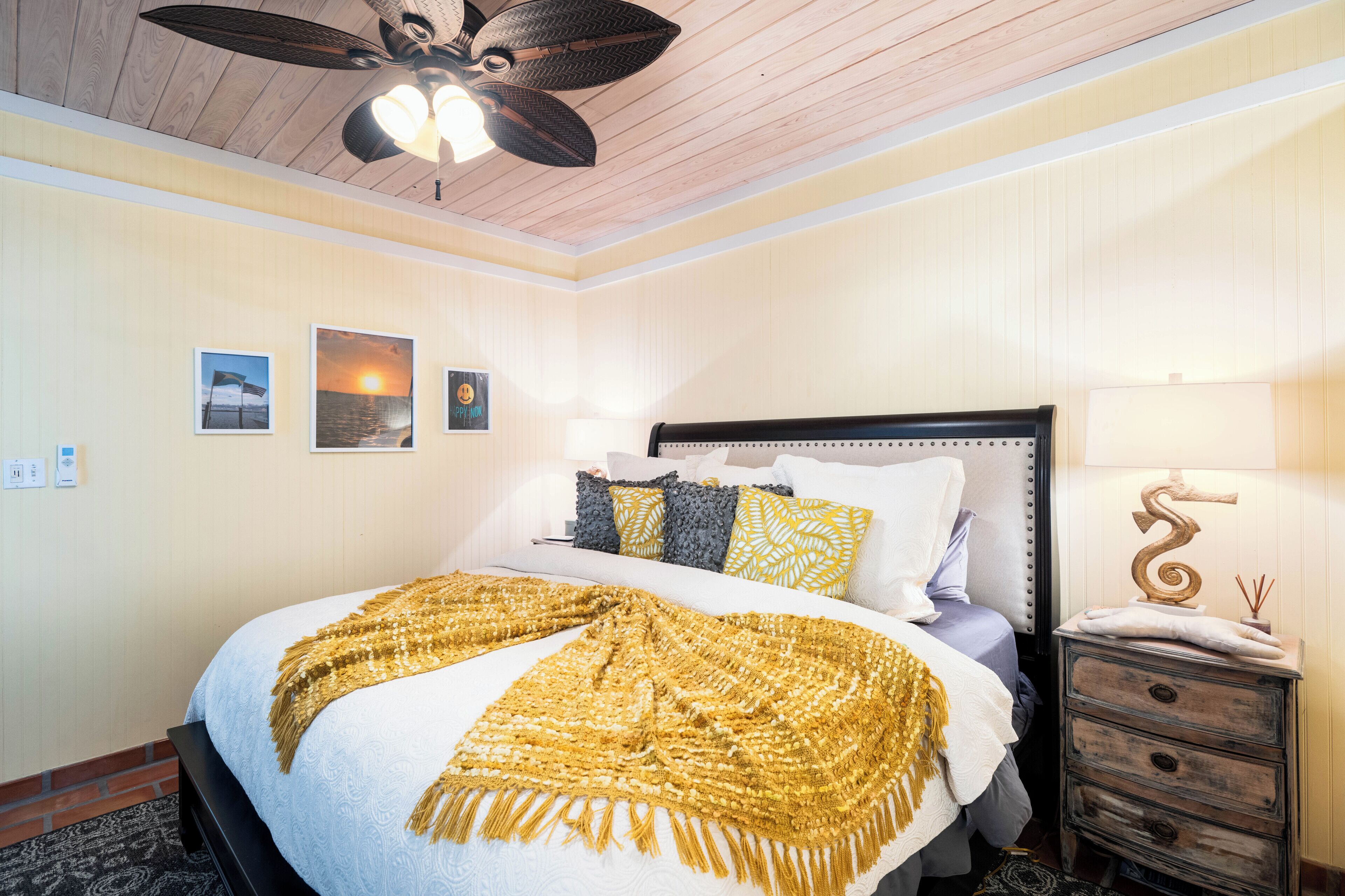 Une chambre à coucher avec un lit, une table de chevet, une lampe et un ventilateur de plafond.
