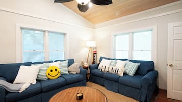 A living room with two blue sofas, a wooden coffee table, and a ceiling fan.