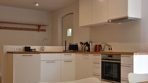 Eine moderne Küche mit weißen Schränken, einem eingebauten Backofen und einer Holzarbeitsplatte.