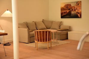 A living room with a sofa, a wooden chair, a lamp, and a painting on the wall. - Exclusive "Steuerbord" vacation rental with private boat access and dock (Boren)