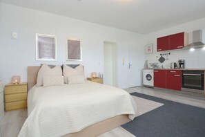 A bedroom with a bed, bedside tables, and a nightstand with a lamp. - City Studio Vesteblick Coburg (Coburg)
