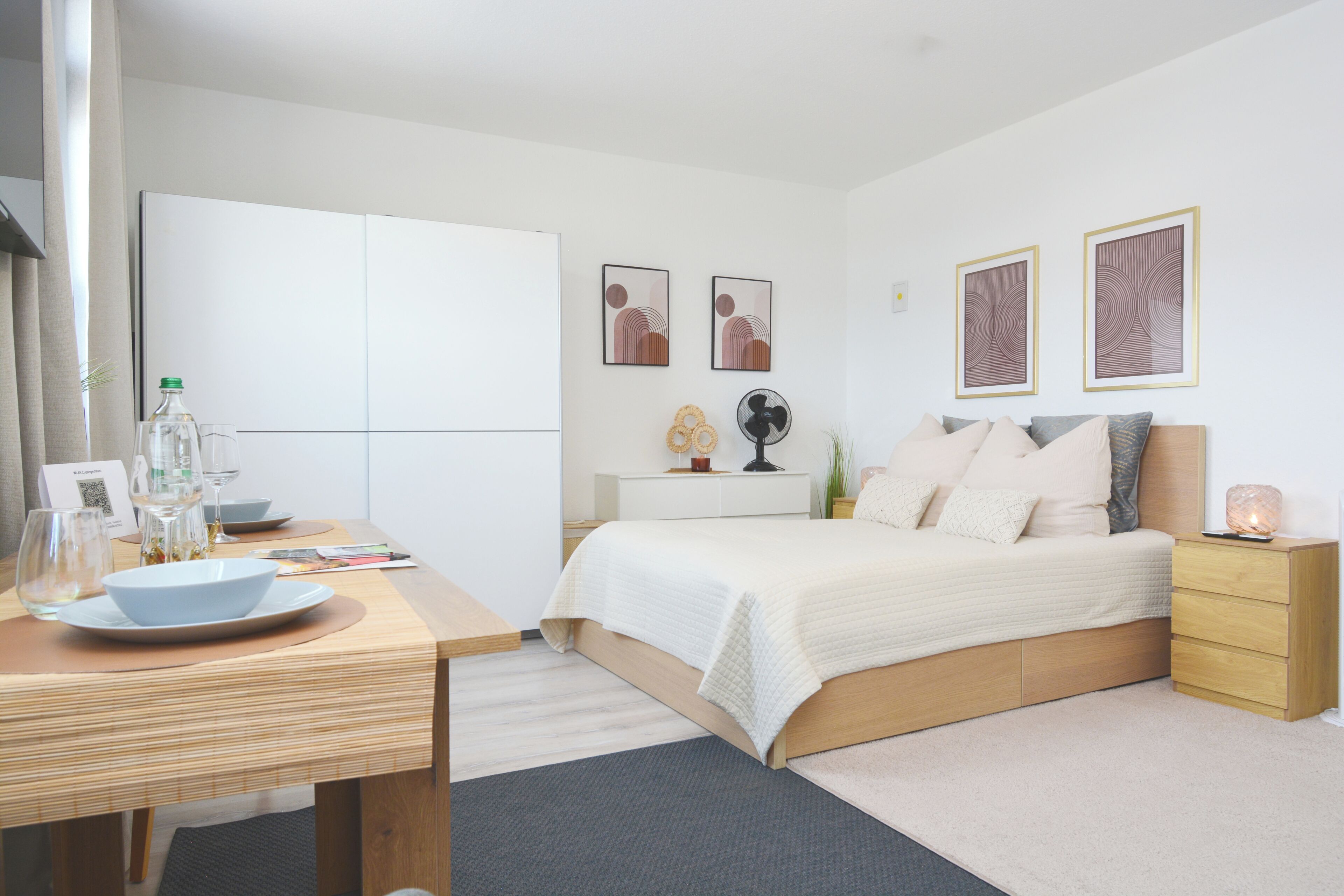 Un dormitorio moderno con una cama, mesitas de noche, un escritorio con una silla y un armario.