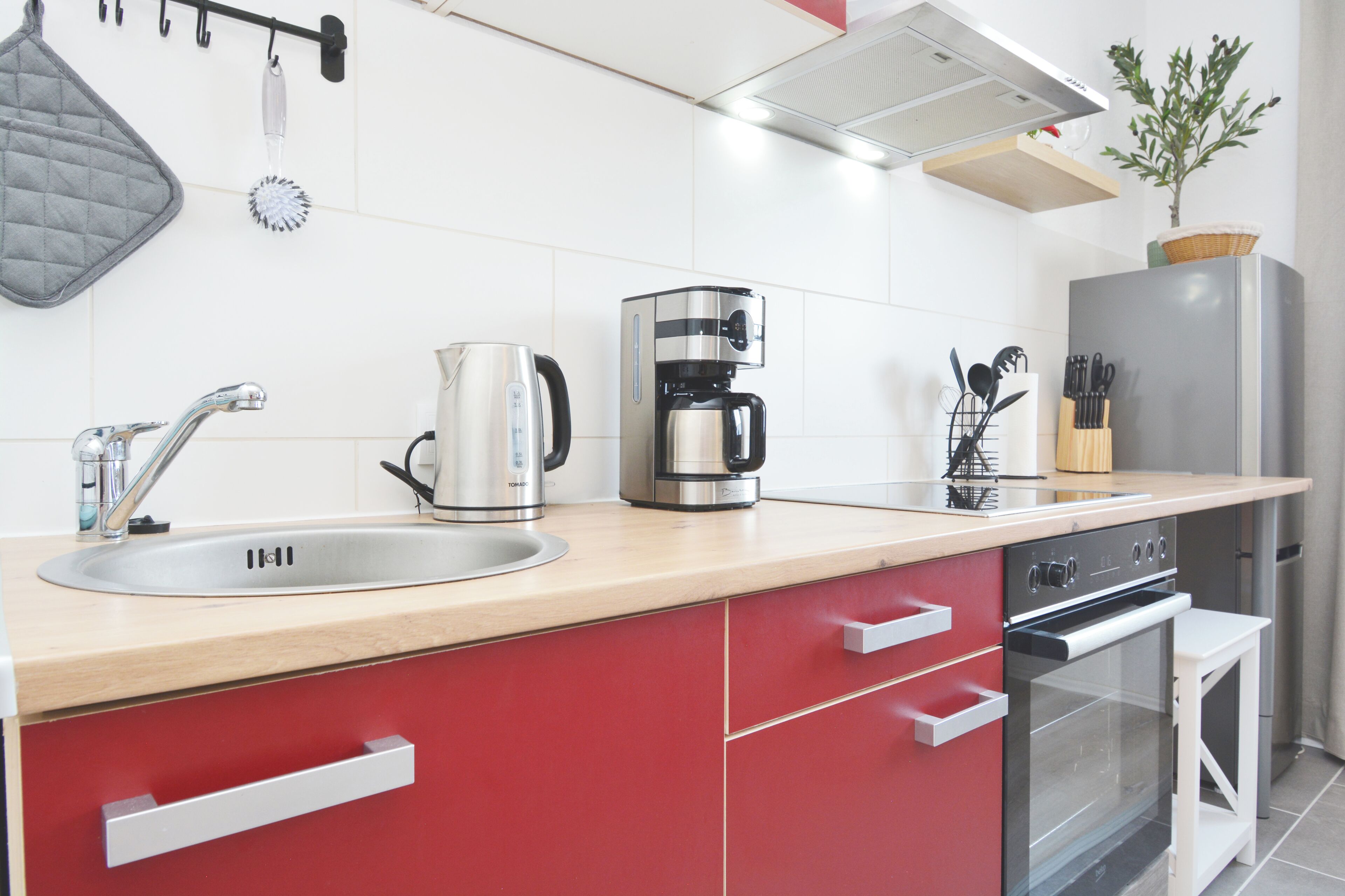 Una cocina moderna con un lavamanos de acero inoxidable, una cafetera y un refrigerador.