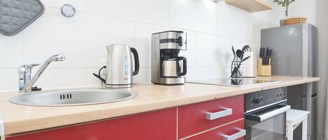 Una cocina moderna con un lavamanos de acero inoxidable, una cafetera y un refrigerador.
