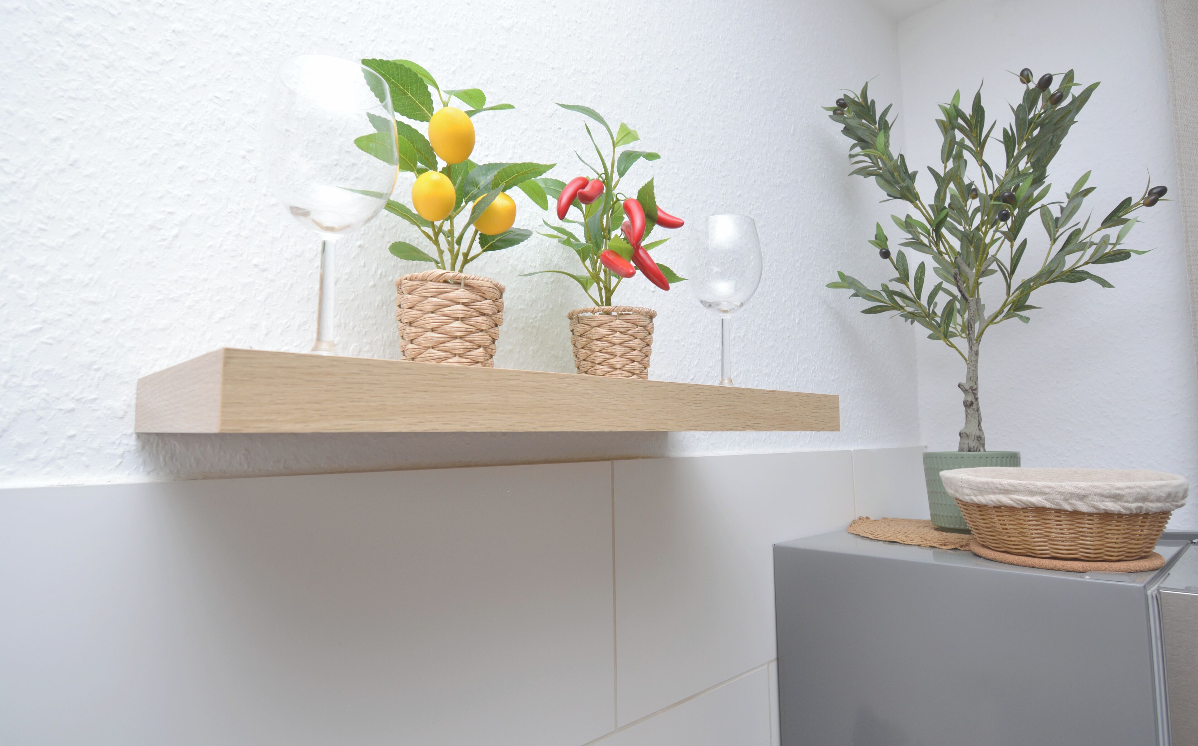 Ein Holzregal mit gewebten Körben, die Pflanzen und ein Glas enthalten.