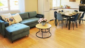 A modern living room with a sofa, a coffee table, and a dining area with chairs and a table set for a meal.