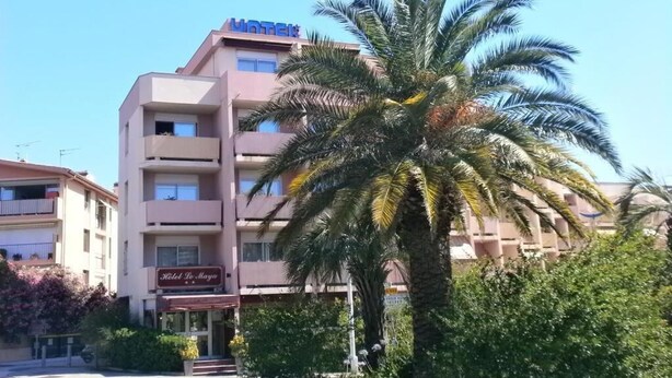 En hotellbyggnad med en skylt som visar texten ”Hotel De Marga”, och en palm på förgrunden.