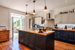 A modern kitchen with a large island, dark cabinetry, stainless steel appliances, and pendant lighting. - House With Private Vineyard (Looe)