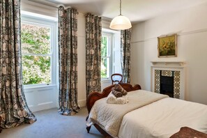 A bedroom with a large bed, a fireplace, and a window with curtains. - House With Private Vineyard (Looe)