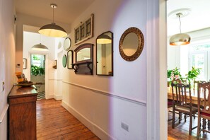 A hallway with wooden flooring, a wooden bench, and a dining table with chairs. - House With Private Vineyard (Looe)