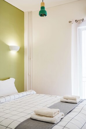 Une chambre d’hôtel avec un lit, une lampe fixée au mur et une fenêtre.