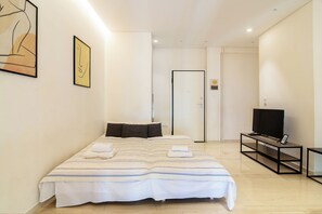 Ein modernes Hotelzimmer mit einem großen Bett, einem Fernseher auf einem Schrank und Kunstwerken an den Wänden.