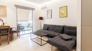 A modern living room with a sectional sofa, a glass coffee table, and a dining area with a wooden table and chairs.