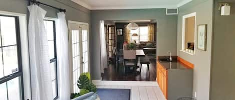 A spacious living area with a dining table, chairs, and a kitchen area with a sink and countertop.