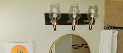 A bathroom with a toilet, sink, mirror, and three wall-mounted lights.