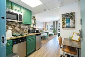 A modern kitchen with green cabinets, stainless steel appliances, and a dining area with a wooden table and chairs. - Relax studio Pool and Lake view 5 min da Universal Free parking no fee resort (Orlando)
