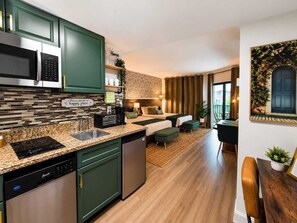 A modern kitchen with a dishwasher, microwave, and a coffee machine. There is a dining area with a table and chairs. - Relax studio Pool and Lake view 5 min da Universal Free parking no fee resort (Orlando)