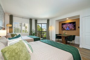 A hotel room with two beds, a balcony, a dining area, and a TV screen displaying fireworks. - Relax studio Pool and Lake view 5 min da Universal Free parking no fee resort (Orlando)