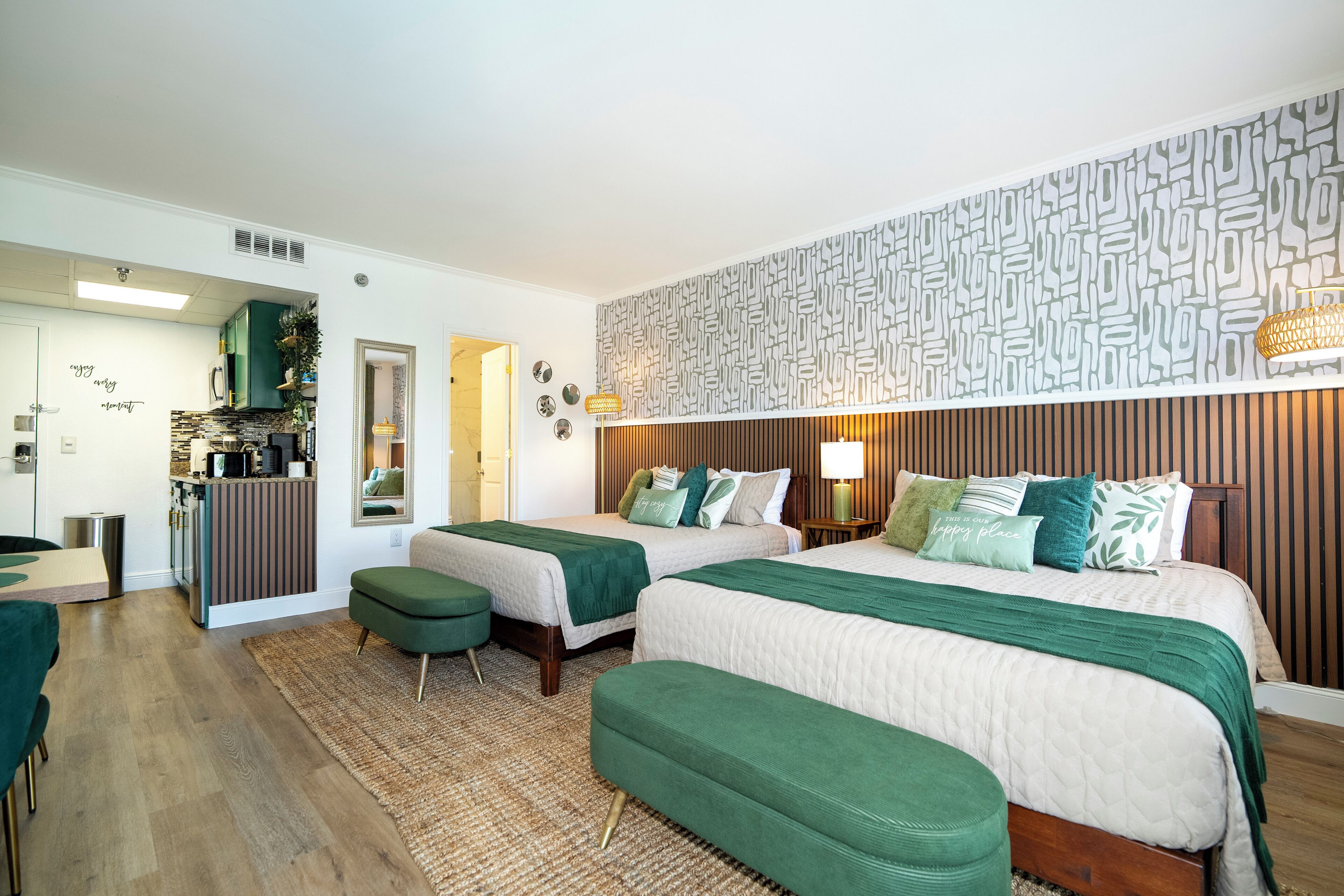 Habitación de hotel con dos camas, kitchenette y baño.