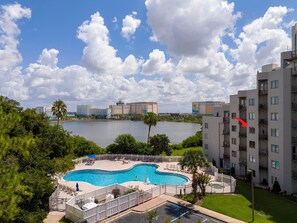 A swimming pool with a white fence, surrounded by greenery, with a view of a lake and buildings in the background. - Relax studio Pool and Lake view 5 min da Universal Free parking no fee resort (Orlando)
