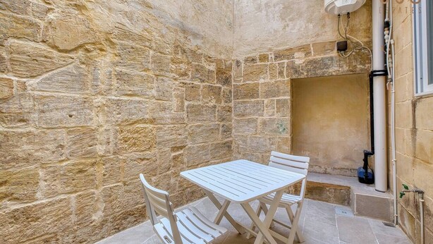 A stone-walled room with a white table and chairs, a water heater, and a window. - Charming 1BR Maltese Maisonette w/ Terrace, Luqa (Ħal Luqa)