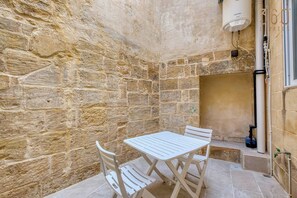 A stone-walled room with a white table and chairs, a water heater, and a window. - Charming 1BR Maltese Maisonette w/ Terrace, Luqa (Ħal Luqa)