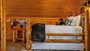 A wooden cabin interior with a bed, a small table, and a fire extinguisher. - Panoramic Views|Hot Tub|Game Room|Resort Pool (Sevierville)