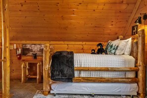 Ein rustikales Holzhütten-Interieur mit Bett, kleinem Tisch und Feuerlöscher.