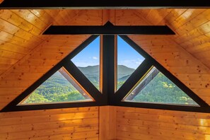 A triangular window with a view of a forested mountain range. - Panoramic Views|Hot Tub|Game Room|Resort Pool (Sevierville)