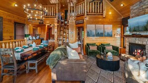 A log cabin interior with a dining area, a fireplace, and a cozy seating arrangement. - Panoramic Views|Hot Tub|Game Room|Resort Pool (Sevierville)