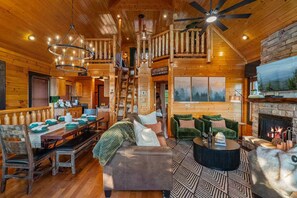 A log cabin interior with a dining area, a fireplace, and a cozy seating arrangement.