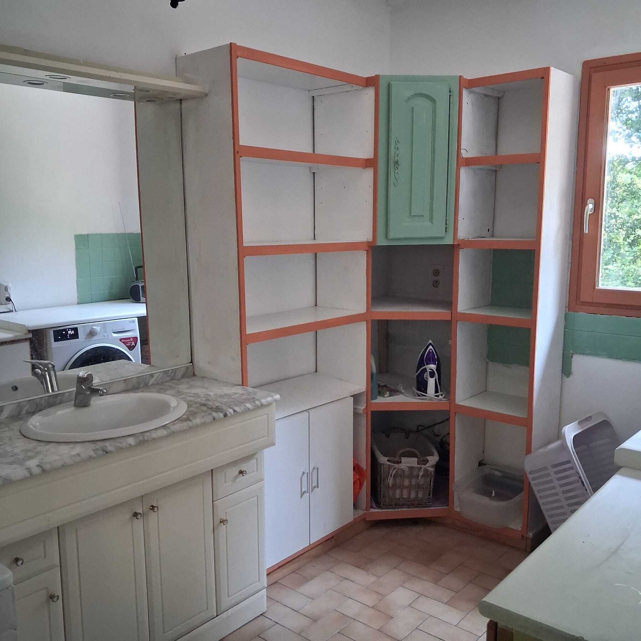Eine kleine Küche mit Spüle, Waschmaschine und einem grünen Schrank.
