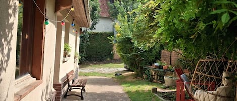 A pathway leading to a house with a bench and a hanging chair.