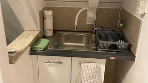 Uma cozinha compacta com pia, escorredor de louça, toalha e um frasco de detergente.