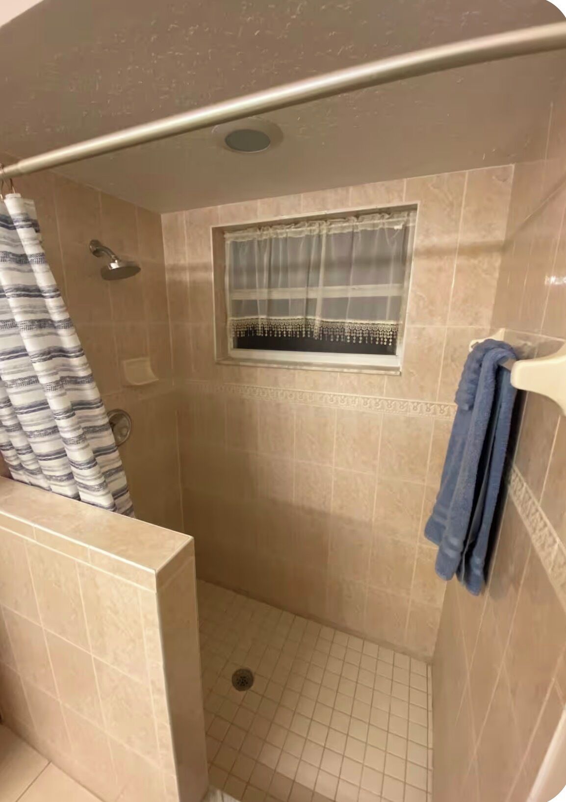 A shower with a window, a towel rack, and a showerhead.