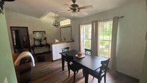 Een eethoek met een tafel, stoelen, een plafondventilator en uitzicht op de omgeving.