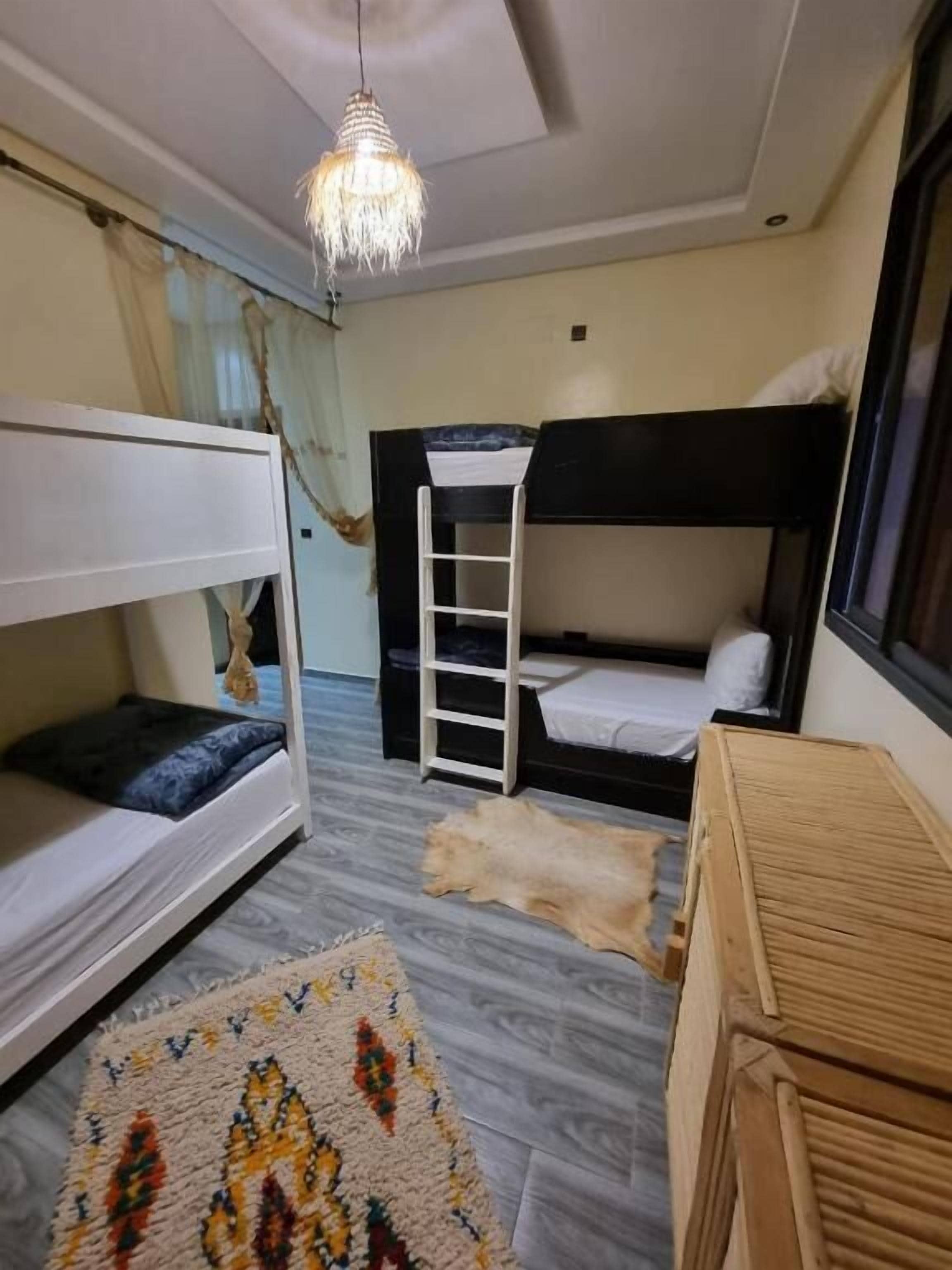Una habitación con literas, una escalera, una lámpara colgante y una alfombra estampada.