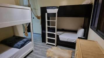 Una habitación con literas, una escalera, una lámpara colgante y una alfombra estampada.