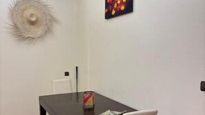 Un comedor con una mesa de madera oscura, una silla blanca y un cuadro en la pared.