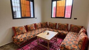 Un salon comprenant un ensemble de canapés, une table basse et un tapis à motifs.