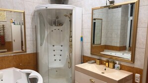 A bathroom with a glass-enclosed shower, a white bathtub, and a vanity with a mirror and sink. - Classical large apartment on art deco Alberta street, FREE locked PARKING (Rīga)