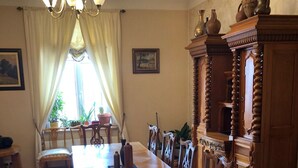 A dining room with a long wooden table, chairs, a chandelier, and a cabinet with decorative items. - Classical large apartment on art deco Alberta street, FREE locked PARKING (Rīga)