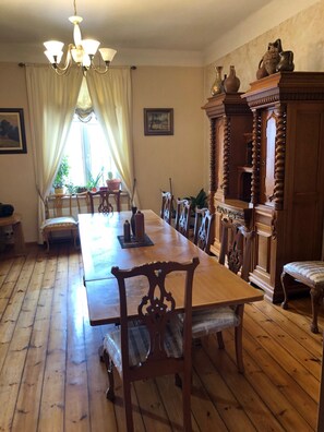 Ein Esszimmer mit einem langen Holztisch, Stühlen, einer Pendelleuchte und einer Vitrine mit Dekoration.