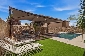 Ein Garten mit Swimmingpool, Gartenmöbeln und einer Pergola, die Schatten spendet.