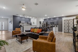Ein modernes Wohnzimmer mit Ledersofa, Couchtisch und Essbereich, im Hintergrund eine Küche.