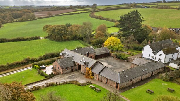 A large farmhouse with multiple buildings, a driveway, and surrounding green fields. - Retreat Near National Parks (Torrington)