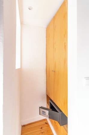 A corner of a room with white walls, a wooden cabinet, and a small black object on the wall.