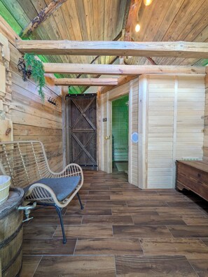A wooden interior with a rustic bench, a wicker chair, and a wooden table. - Kierunek Puszcza 2 Apartments - Hot Tub, Sauna, Salt Cave - up to 14 people (Narewka)