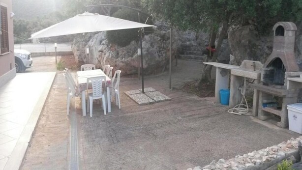 An outdoor patio with a table and chairs, a barbecue grill, and a stone wall. - Villa Cloe: For Those Who Love Peace and Quiet (San Vito Lo Capo)